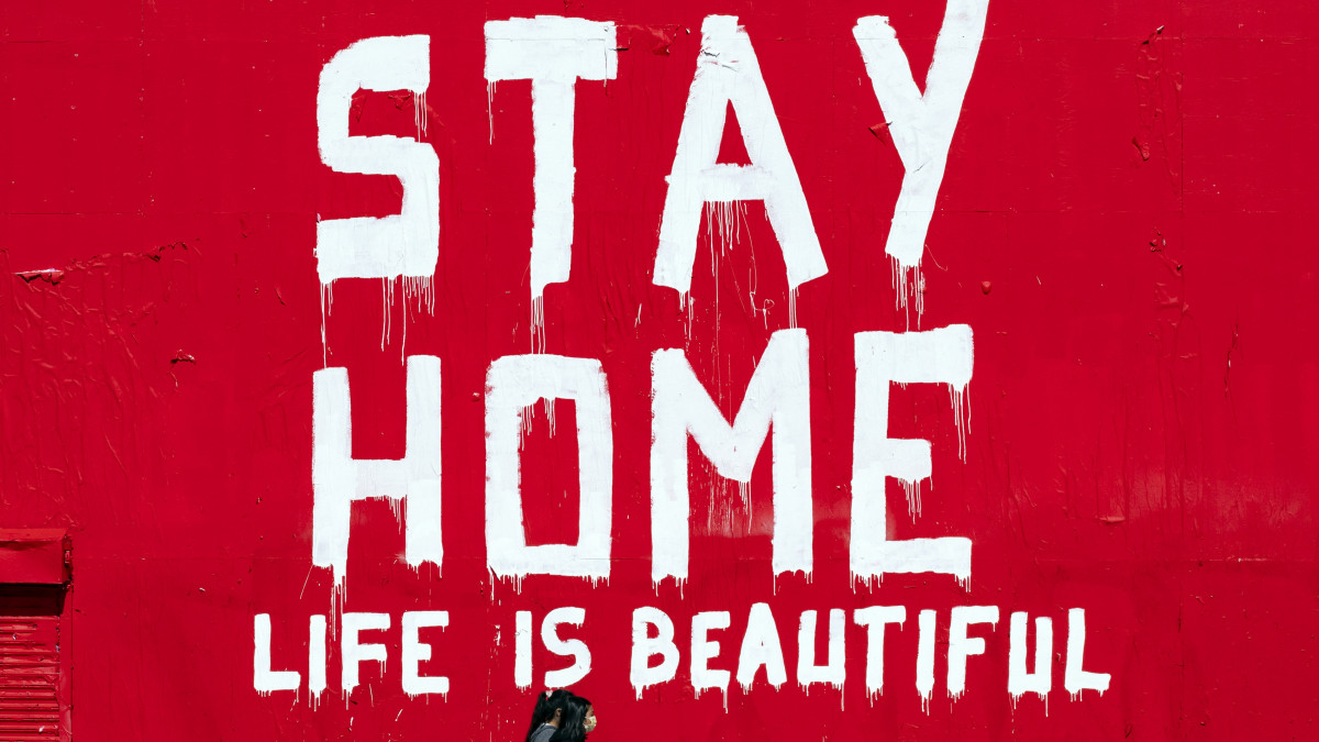Maradj otthon - Az élet gyönyörű feliratú falfestmény előtt megy két nő Los Angelesben 2020. április 7-én, a koronavírus-járvány idején.