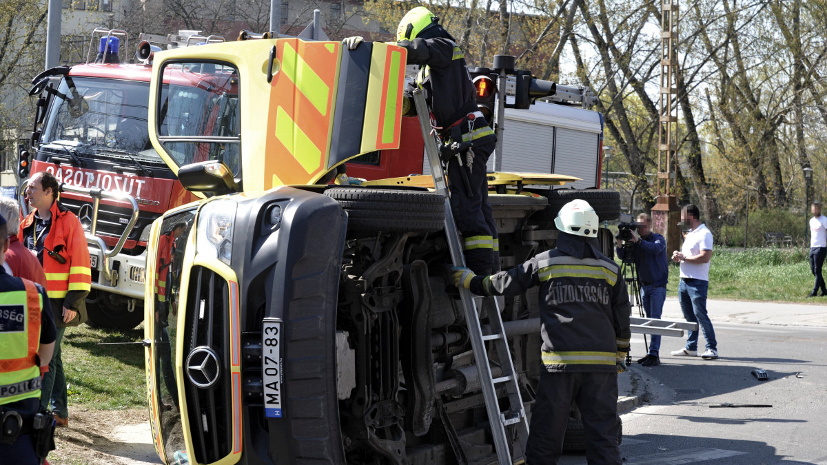 Tűzoltók felborult mentőautónál a főváros XIV. kerületében, az Egressy út és Miskolci utca kereszteződésében 2020. április 8-án. A mentőautó előzőleg összeütközött egy személyautóval, a balesetnek sérültje is van.