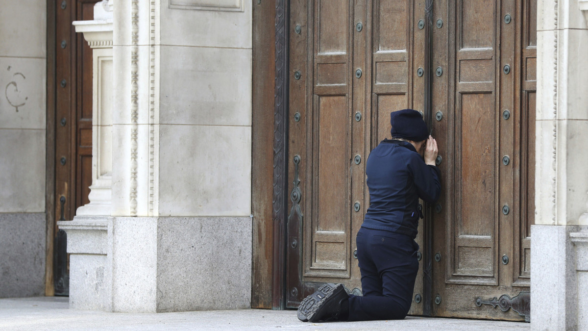 Nő imádkozik a Westminster-székesegyház bezárt kapuja előtt húsvétvasárnap 2020. április 12-én. a koronavírus-járvány miatt egy Egyesült Királyságban kijárási korlátozásokat rendeltek el, a templomok többsége az interneten közvetíti az istentiszteletet.
