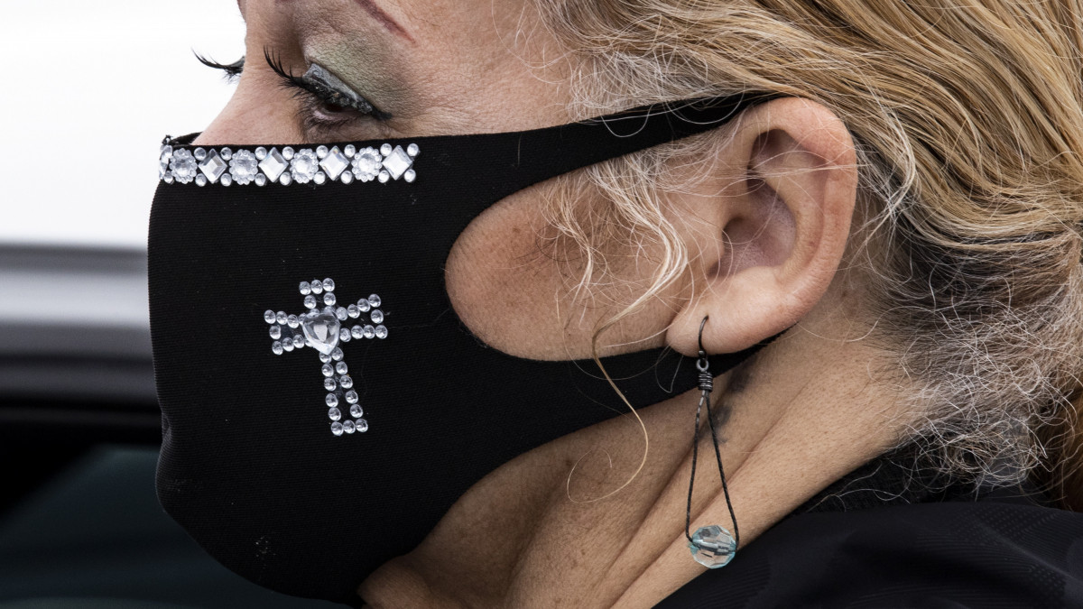 Kereszt formájú díszítéssel ellátott védőmaszkot visel egy nő a koronavírus-fertőzés elleni védekezésül a kaliforniai Newark egyik parkolójában tartott húsvéti misén 2020. április 12-én.