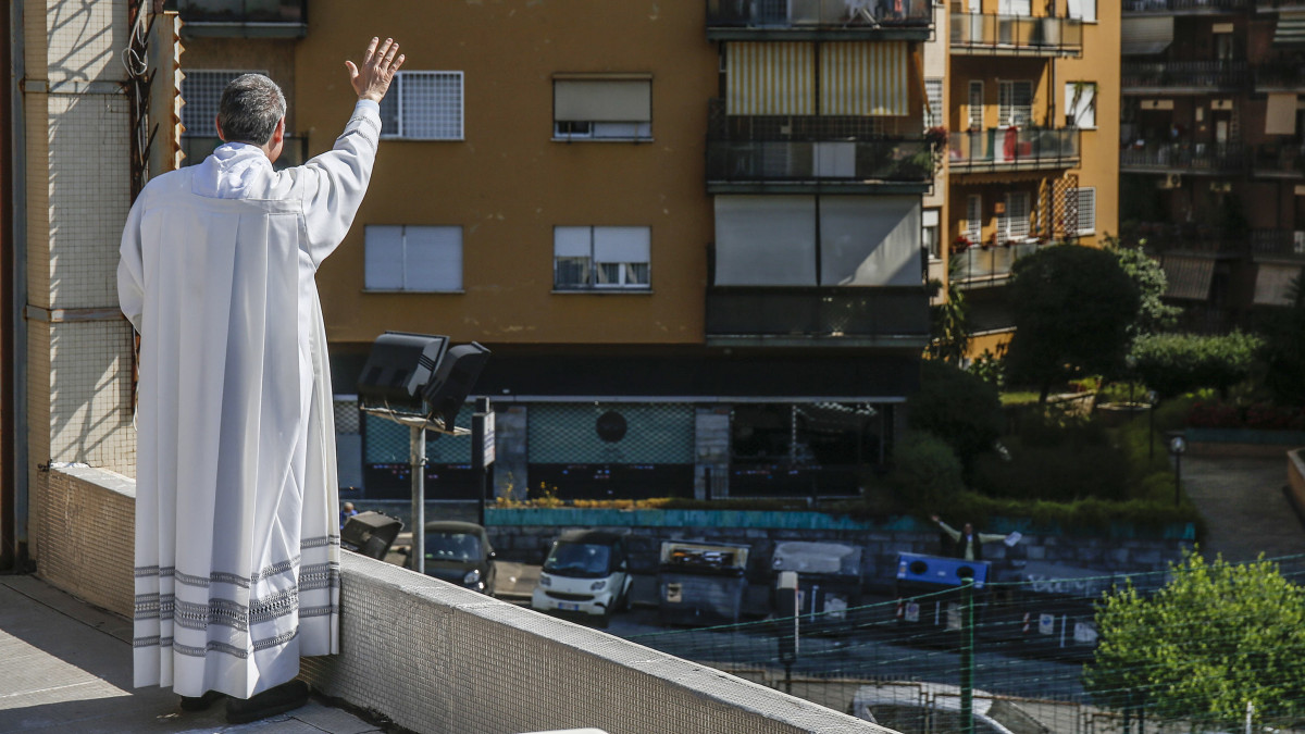 A hívőket üdvözli  egy olasz pap, aki a koronavírus-járvány érdekében bevezetett kijárási korlátozások miatt egy épület tetőteraszán cerebrálja a húsvéti szentmisét Rómában 2020. április 12-én.