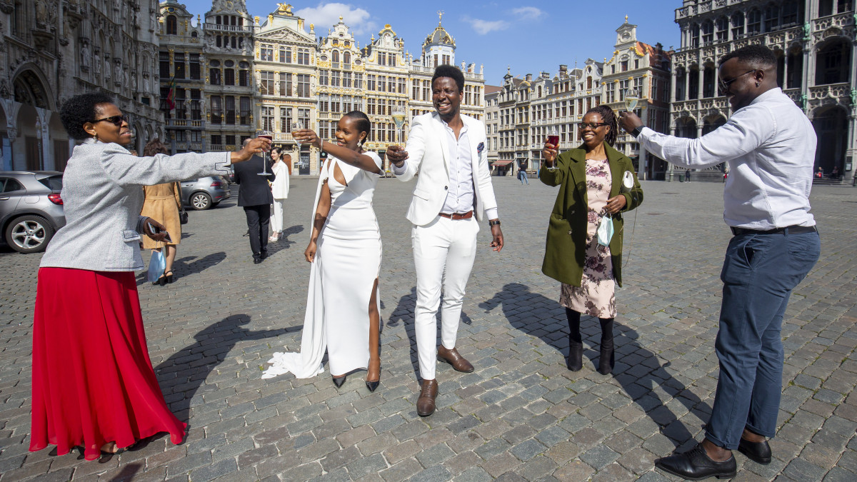 Újdonsült házaspár koccint barátaival az esküvője után a brüsszeli városháza előtt, a Grand Place-on a koronavírus-járvány idején, 2020. április 4-én. Belgiumban kijárási korlátozás van érvényben, az esküvőket is csak szűk körben lehet megtartani.