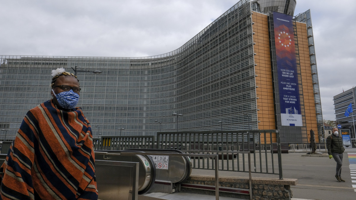 Védőmaszkot viselő nő halad el az Európai Bizottság épülete előtt Brüsszelben 2020. április 14-én. A koronavírus-járvány megfékezése érdekében Belgiumban április 19-től kijárási korlátozásokat vezetnek be.