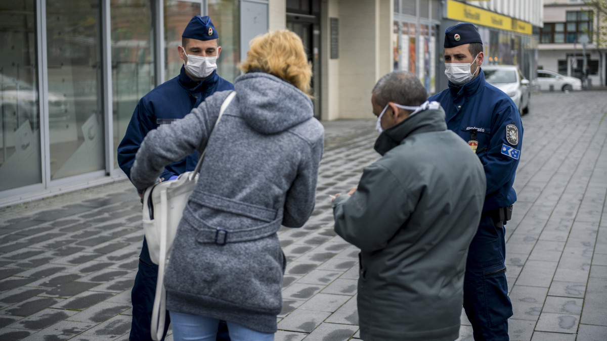 Járőröző rendőrök járókelőket igazoltatnak a pécsi Kossuth téren 2020. április 14-én. A koronavírus-járvány miatt március 28-án kihirdetett kijárási korlátozást a kormány április 9-én határozatlan időre meghosszabbította.