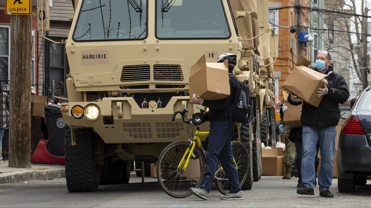A hadsereg által kiosztott élelmiszercsomagokat viszik haza a Massachusetts állambeli Chelsea rászoruló lakói 2020. április 20-án, miután a koronavírus-járvány miatt bezártak az üzletek, és sokan elveszítették a munkájukat.