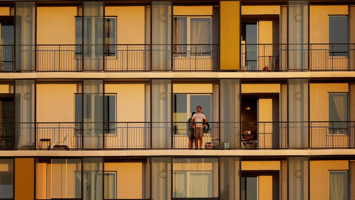 Férfi nézi a naplementét lakásának az erkélyéről Bukarestben 2020. április 6-án, a koronavírus-járvány miatt bevezetett kijárási korlátozás idején.