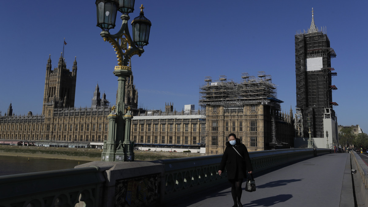 A londoni Westminster hídon, a parlament előtt megy egy járókelő a koronavírus-járvány idején, 2020. április 21-én, amikor újra ülésezik a törvényhozás. A fertőzésveszély miatt kijárási korlátozás van érvényben Nagy-Britanniában, ezért a törvényhozók és a parlamenti dolgozók legnagyobb része is otthon tartózkodik, és a képviselők most is csak virtuálisan, az interneten keresztül összekapcsolódva ülnek össze.