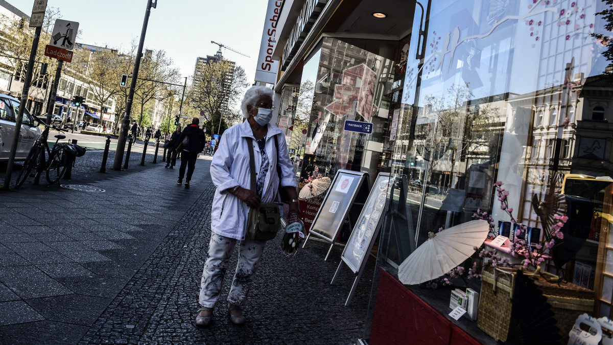 Járókelő egy kinyitott berlini üzlet kirakata előtt a koronavírus-járvány idején, 2020. április 22-én, amikor a német hatóságok engedélyezték a 800 négyzetméternél nem nagyobb eladótérrel rendelkező boltoknak a járvány miatti több hetes zárva tartás utáni újranyitást.