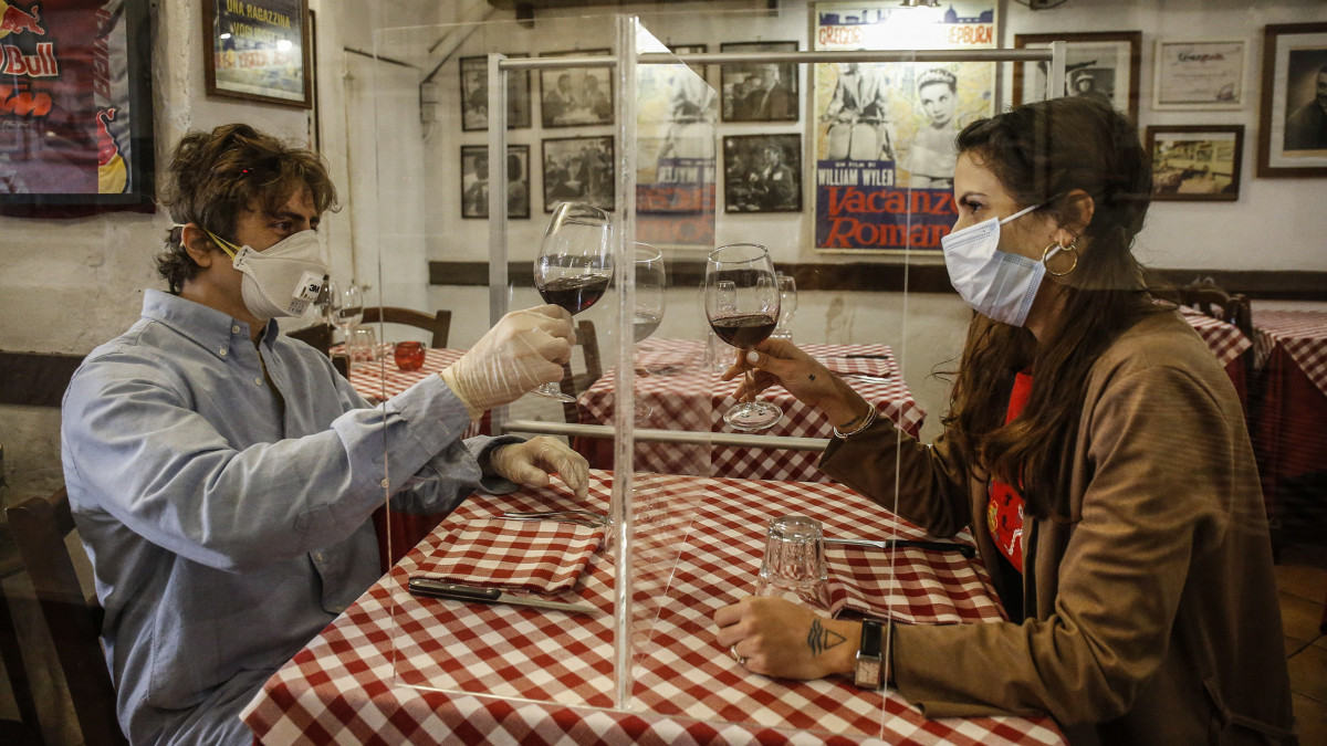 Valerio Calderoni tulajdonos és felesége, Martina teszteli a fertőzésveszély elkerülésének érdekében állított plexifalat a római éttermükben 2020. április 23-án.