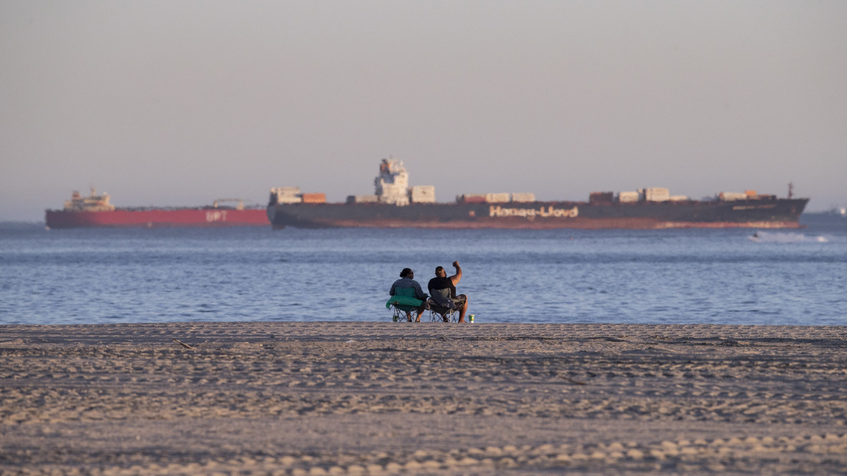 Olajszállító hajókat néz egy pár a kaliforniai Huntington Beach partjainál 2020. április 24-én. A koronavírus miatt jelentősen visszaesett az olaj iránti kereslet, mintegy három tucat olajszállító vesztegel Long Beach és San Francisco között mert nem tudják hova szállítani a rakományt.