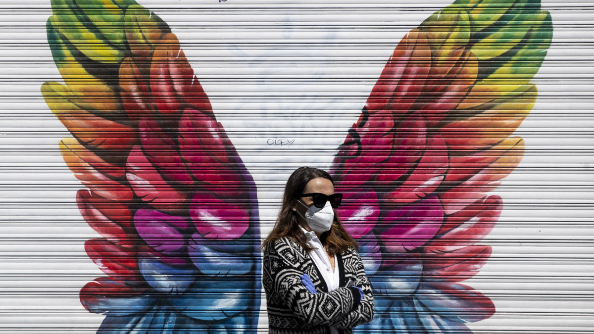 Védőmaszkot viselő nő egy bezárt madridi üzlet előtt 2020. április 25-én, a koronavírus-járvány idején.