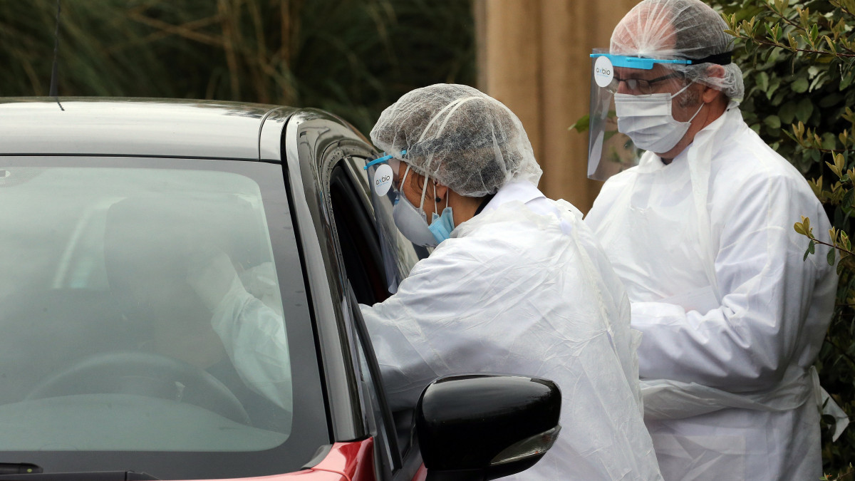Védőruhát viselő egészségügyi dolgozók autósokat tesztelnek a délnyugat-franciaországi Anglet város biológiai laboratóriuma előtt létesített autós tesztállomáson 2020. április 20-án, a koronavírus-járvány idején.