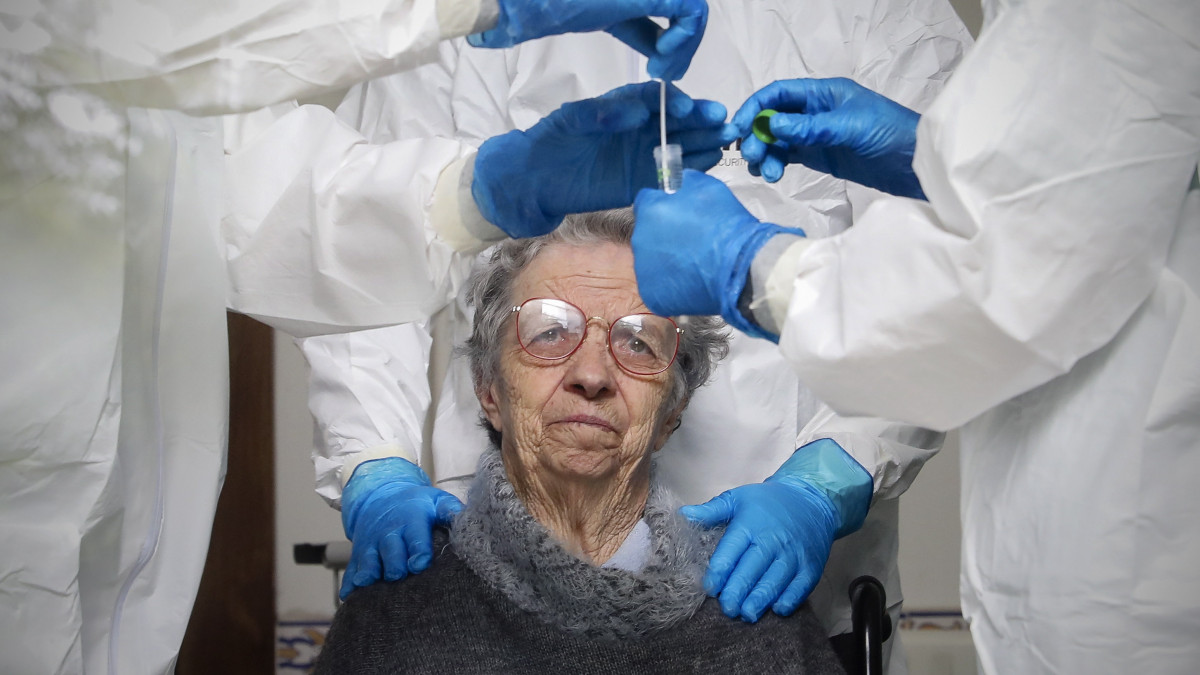 Védőruhát viselő egészségügyi dolgozó vizsgálati mintát vesznek egy lakótól a portugáliai Santa Maria da Feira egyik idősek otthonában 2020. április 17-én, a koronavírus-járvány idején.