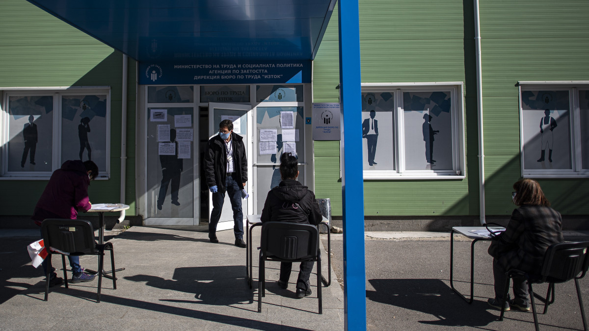 A koronavírus-járvány miatt orrukat-szájukat védő ügyfelek nyomtatványokat töltenek ki egy szófiai munkaügyi hivatal előtt 2020. április 8-án. A járvány miatt elrendelt védekező intézkedések bevezetése óta mintegy 44 ezer ember vált munkanélkülivé Bulgáriában.