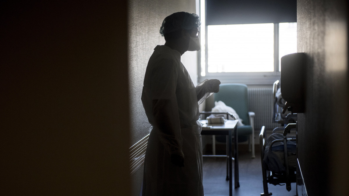 Koronavírussal fertőzött beteggel beszél egy védőruhás nővér a Párizs melletti Bagnolet Floral Klinikájának elkülönítőjében 2020. április 22-én.