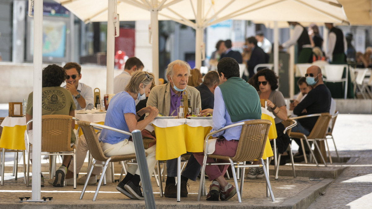 Együtt ebédel egy társaság Lisszabon egyik éttermének kerthelyiségében 2020. május 18-án, miután néhény nappal korábban megkezdődött a koronavírus-járvány miatt bevezetett korlátozások fokozatos feloldása. Kinyitottak az üzletek, kávézók, éttermek, valamint az óvodák és az iskolák egy része.
