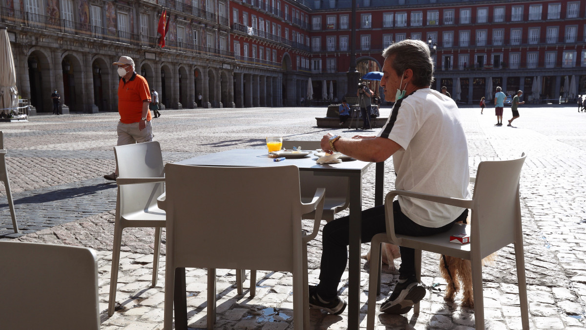 Vendég ül kutyájával a madridi Plaza Mayor egyik bárjának teraszán 2020. május 25-én, a koronavírus-járvány idején. Spanyolországban tovább folytatódtak a járványügyi enyhítések, Madrid és Barcelona is a lazítások újabb, egyes szakaszába lépett.