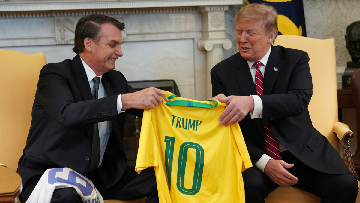 Jair Bolsonaro brazil elnök (b) egy 10-es számú, Trump feliratú brazil focimezt ajándékoz Donald Trump amerikai elnöknek a washingtoni Fehér Házban tartott találkozójukon 2019. március 19-én.