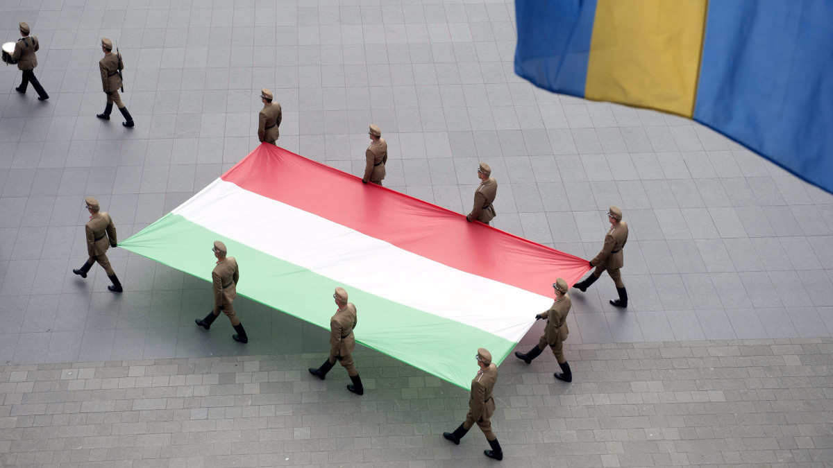 Magyarország lobogójának ünnepélyes felvonása az Országház előtt, a Kossuth Lajos téren 2015. június 4-én, a nemzeti összetartozás napján, a trianoni békediktátum 95. évfordulóján. A kép előterében egy székely zászló.