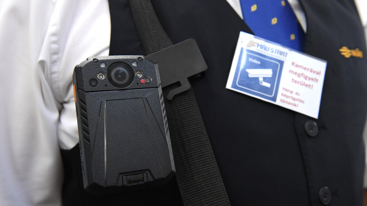Testkamera és a felvételre figyelmeztető kártya a bemutató sajtótájékoztatón, a Keleti pályaudvaron 2019. augusztus 30-án. A vasúti menetjegyellenőröket ért támadások miatt szeptember 1-jétől 103 új testkamerát kapnak országszerte a MÁV-START Zrt. jegykezelői.