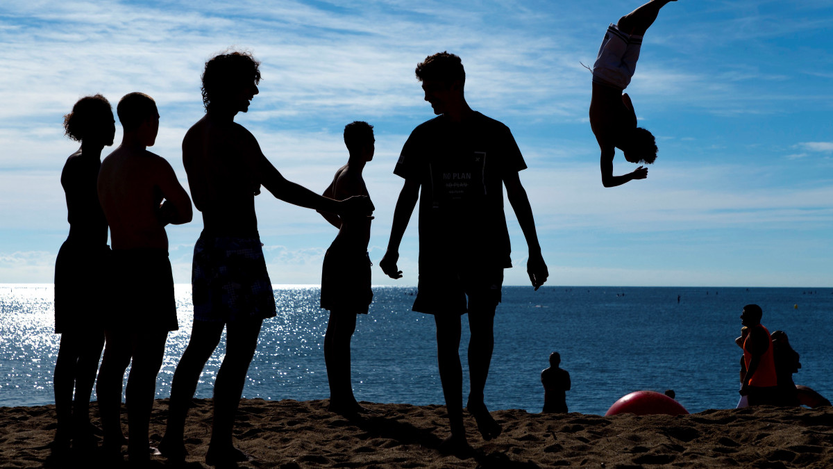 Fiatalok akrobatikus ugrásokat végeznek a barcelonai Barcelonata tengerparti strandon 2020. június 5-én. A koronavírus-járvány miatt bevezetett korlátozásokat fokozatosan oldják fel Spanyolországban.
