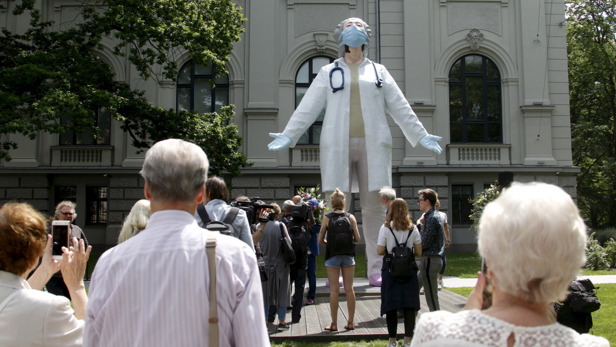 Emberek nézik a hat méter magas, ápolónőt ábrázoló szobrot a rigai Nemzeti Szépművészeti Múzeum kertjében 2020. június 16-án. Az Aigars Bikse szobrász által készített szobor a lett társadalomnak az egészségügyi dolgozók önzetlen munkája iránt érzett háláját fejezi ki.