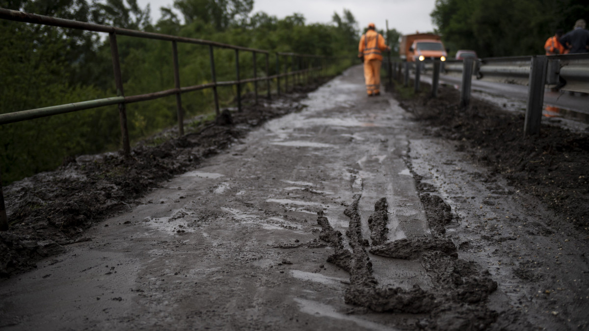 A Magyar Közút Nonprofit Zrt. munkatársai takarítják a kővel, sárral, hordalékkal elöntött 12-es főutat és a mellette húzódó kerékpárutat a Pest megyei Zebegénynél 2020. június 18-án. Az utat lezárták a 18-as kilométernél, Zebegény határában. A heves esőzés miatt a lezúduló kő- és sárlavina megrongálta a vasúti töltést is, pótlóbuszok közlekednek Szob és Nagymaros között.