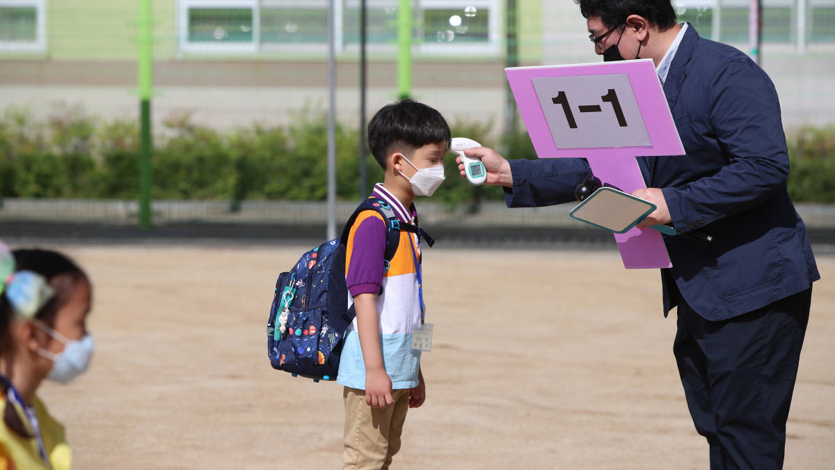 Első osztályos diák testhőmérsékletét mérik egy tegui általános iskola udvarán 2020. május 27-én. Dél-Koreában újranyitottak a koronavírus-járvány miatt még zárva tartó óvodák, valamint az általános és középiskolák.