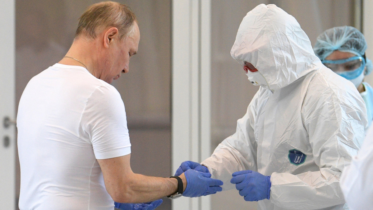 Vlagyimir Putyin orosz elnök (k) kesztyűjét segít levenni egy szakember, miután az államfő meglátogatta azokat a pácienseket, akiket koronavírus-fertőzés gyanújával megfigyelés alatt tartanak egy moszkvai kórházban 2020. március 24-én. A hivatalos adatok szerint a fertőzöttek száma egy nap alatt 57-tel, 495 főre nőtt. Az érintettek közül 290-en Moszkvában tartózkodnak.