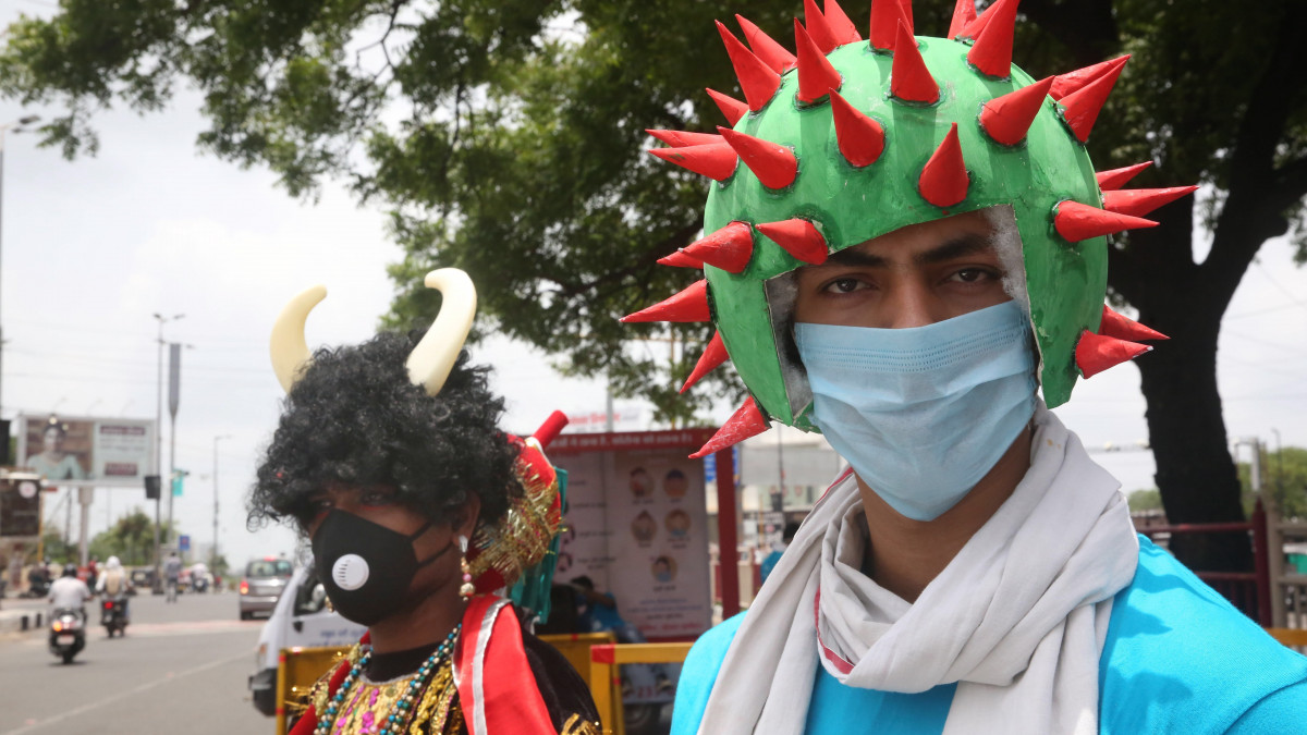 Koronavírust formázó fejfedőben hívja fel az emberek figyelmét a vírus terjedésének veszélyére egy egészségügyi alkalmazott az indiai Bhopalban 2020. július 10-én.