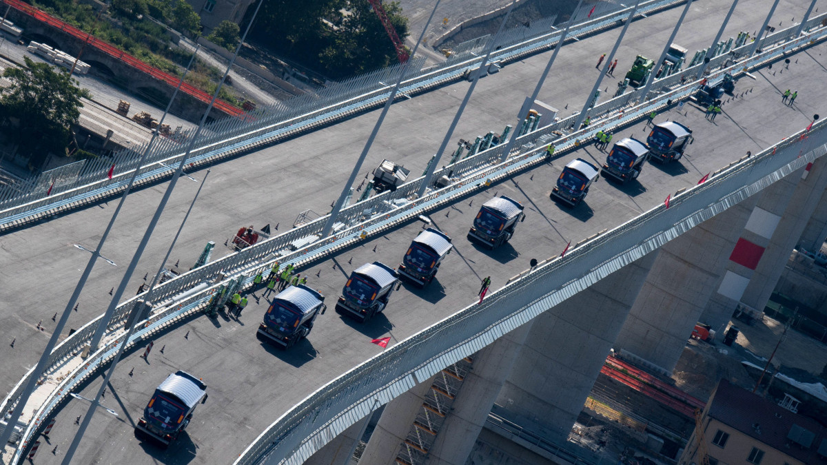 Nyergesvontató kamionok haladnak át az új genovai autópályahídon 2020. július 19-én. Ötvennégy ilyen teherautó teszi próbára egy héten át az új hidat. 2018. augusztus 14-én ismeretlen okból leszakadt a Morandi-hídból egy 210 méteres szakasz, autók zuhantak a mélybe, 43 ember életét vesztette. Az új, tartókábel nélküli acélhíd Renzo Piano olasz építész tervei alapján készül.