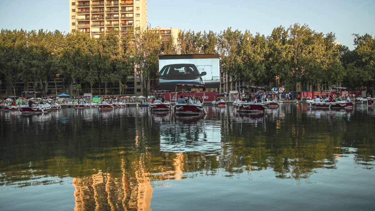 Szabadtéri mozi a vízen csónakokban ülő nézőkkel Párizsban 2020. július 18-án, miután a városban megnyitották a szokásos nyári plázsokat. A mesterséges vízparti strandok szigorú járványügyi szabályok betartásával működhetnek.