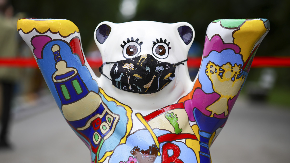 Szájmaszkot viselő mackó az Egyesült Buddy Mackók (United Buddy Bears) című szabadtéri kiállítás megnyitóján a 65. fennállását ünneplő berlini Tierpark Állatkertben 2020. július 2-án. A Buddy (pajtás) mackók szobrait különböző országok művészei alkották a tolerancia és a nemzetek közötti megértés elősegítése érdekében. Az öt kontinens 33 országában tartott bemutatók után a berlini állatkertben 147 mackószobrot tekinthetnek meg a látogatók. A szobrokat elárverezik, és a befolyt pénzt az ENSZ gyermekalapja, az UNICEF javára fordítják.