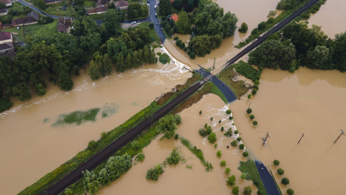 A nagy esőzés miatt vízzel elárasztott és megrongálódott út Zalaszentjakabon 2020. július 25-én. Középen a Budapest-Nagykanizsa vasútvonal része látható.