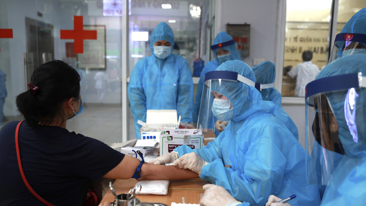 Koronavírusteszthez szükséges vérmintát vesz egy nőtől egy védőöltözetet viselő egészségügyi dolgozó Hanoiban 2020. július 31-én. A vietnami állami televízió közlése szerint ezen a napon hunyt el az első ember koronavírus-fertőzés miatt az országban. A 95 milliós lakosságú Vietnamban mindeddig sikeres volt a járvány elleni védekezés.