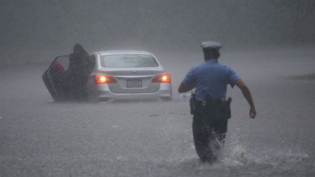 Philadelphia, 2020. augusztus 4.Rendőr siet a térdig érő vízben egy elakadt járművezetőnek segíteni az Ézsaiás trópusi vihar elvonulása után Philadelphiában 2020. augusztus 4-én. Pennsylvania államban a vihar számos településen áradásokat okozott.