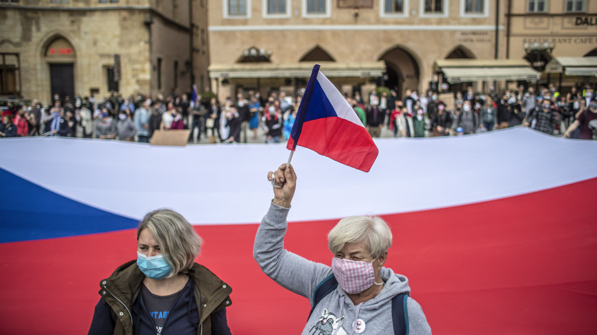 Védőmaszkot viselő nők állnak a cseh zászló előtt az Andrej Babis cseh kormányfő és a cseh kormány elleni tüntetésen Prága belvárosában 2020. június 9-én. A tüntetésen több száz ember tiltakozott a kormány koronavírus-járvánnyal kapcsolatos intézkedései miatt. A prágai tüntetésen kívül még több helyen is tartottak demonstrációt az országban.