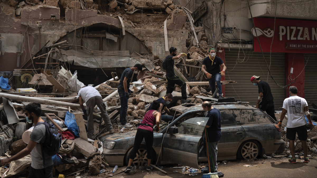A romokat takarítják el emberek egy összeomlott lakóház elől Bejrútban 2020. augusztus 7-én, három nappal a kikötői negyedben történt hatalmas erejű, kettős robbanás után. A detonációk következtében elhunytak száma 154-re emelkedett, több mint ötezren megsebesültek. Bejrútot katasztrófa sújtotta várossá nyilvánították.