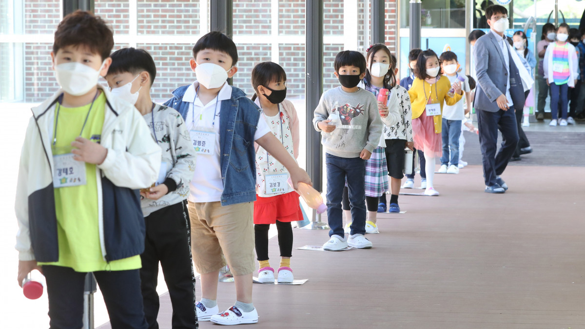 Kisdiákok állnak sorban egymástól biztonságos távolságra egy szöuli általános iskola ebédlője előtt 2020. május 27-én. Dél-Koreában újranyitottak a koronavírus-járvány miatt még zárva tartó óvodák, valamint az általános és középiskolák.