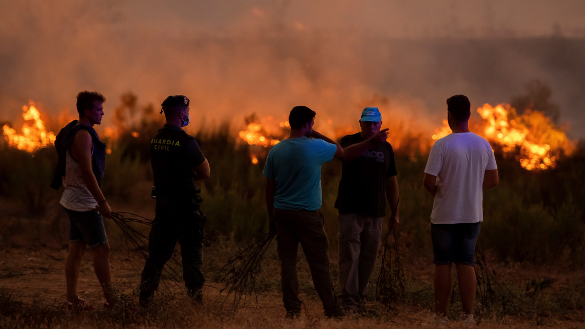 Rendőrök és helyiek a dél-spanyolországi Almonaster la Real településen és környékén pusztító erdőtűz helyszínén 2020. augusztus 27-én. A környékről mintegy 200 embert kellett evakuálni.