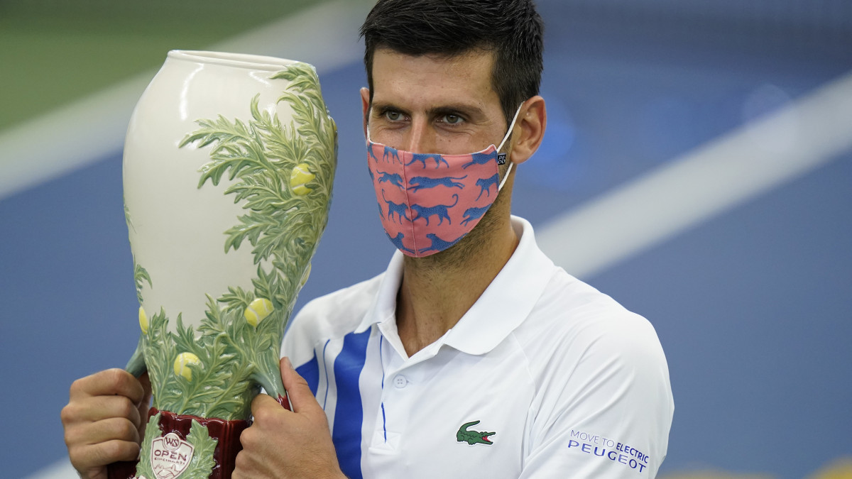 Novak Djokovic védőmaszkban és a bajnoki trófeával a kezében az eredményhirdetésen a New York állambeli Flushing Meadows-ban 2020. augusztus 29-én.