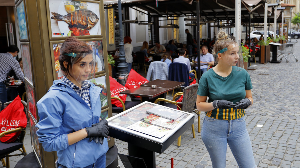 Étterem terasza előtt várnak vendégekre pincérek a bukaresti Óvárosban 2020. június 1-jén, amikor a koronavírus-járvány miatt bevezetett korlátozások enyhítéseként a hatóságok engedélyezték a vendéglátóhelyek teraszainak kinyitását Romániában.