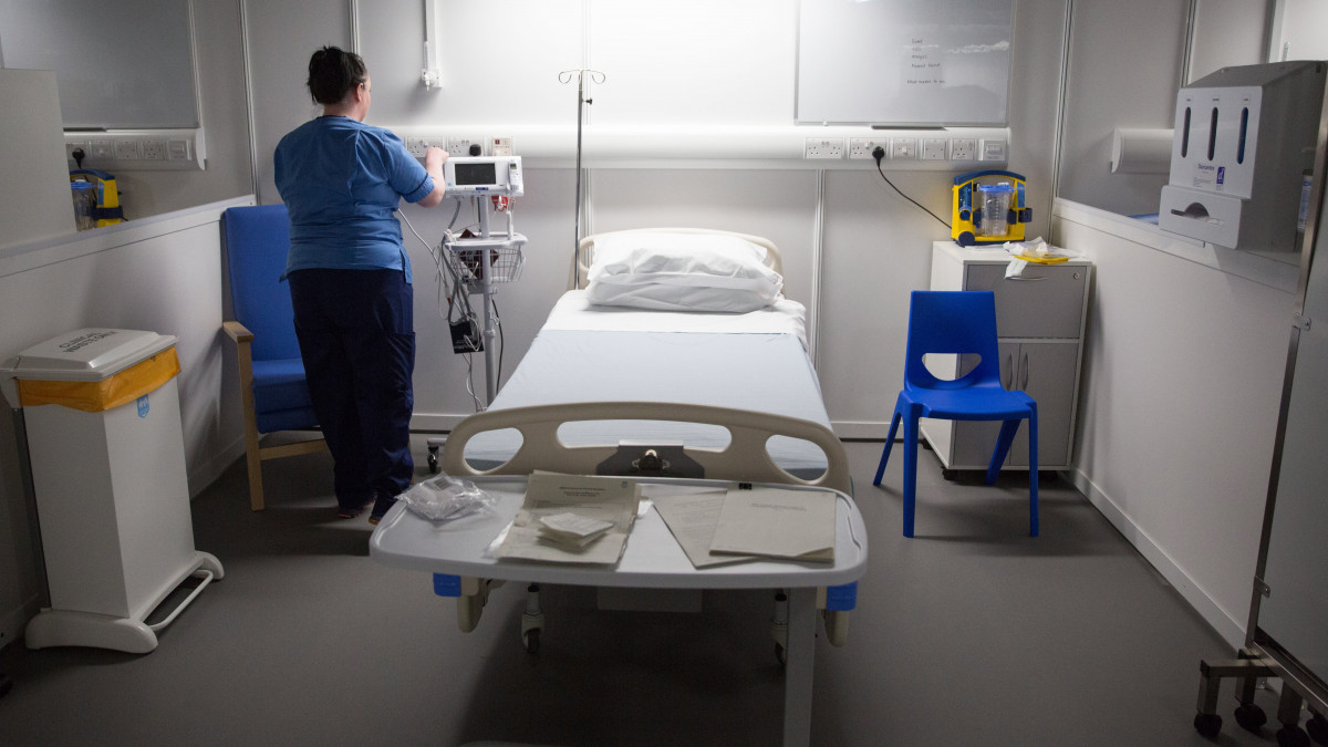 Egészségügyi alkalmazott a Glasgow-i SEC konferenciaközpontból kialakított ideiglenes kórház egyik ágyánál 2020. április 20-án, a megnyitás előtt. A koronavírussal fertőzött betegek kezelésére létrehozott kórház építése 43 millió angol fontba került.