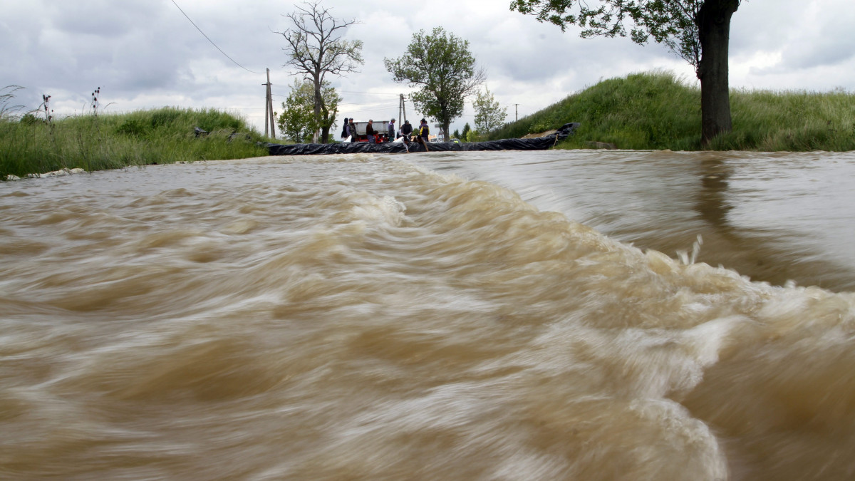 Víz hömpölyög a Hernád áradása miatt ideiglenes védőgáttal lezárt, Hernádszentandrás és Pere közötti úton 2014. május 18-án.
