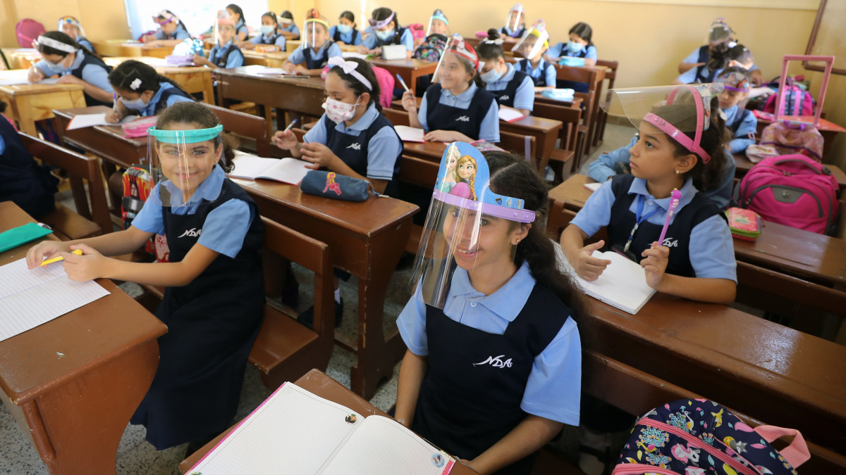 A koronavírus-járvány miatt védőmaszkot és arcvédő pajzsot viselő tanulók a kairói Notre Dame iskola első tanítási napján, 2020. október 19-én. A járvány miatt márciustól az összes oktatási intézmény zárva volt Egyiptomban.