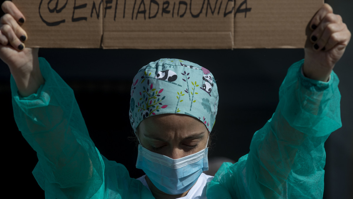 A koronavírus-járvány miatt védőmaszkot viselő egészségügyi dolgozó feltart egy táblát, miközben magasabb fizetést és jobb munkakörülményeket követel a madridi La Paz kórház bejárata előtt 2020. október 5-én. A kórház intenzív osztálya újra megtelt koronavírussal fertőzött betegekkel.