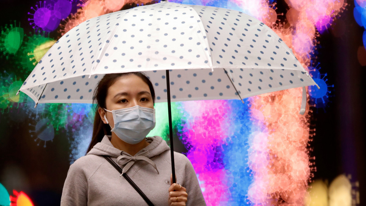 Háttér-homályosítással készített képen egy védőmaszkos nő sétál esernyővel Tajpejben 2020. április 23-án, a koronavírus-járvány idején.