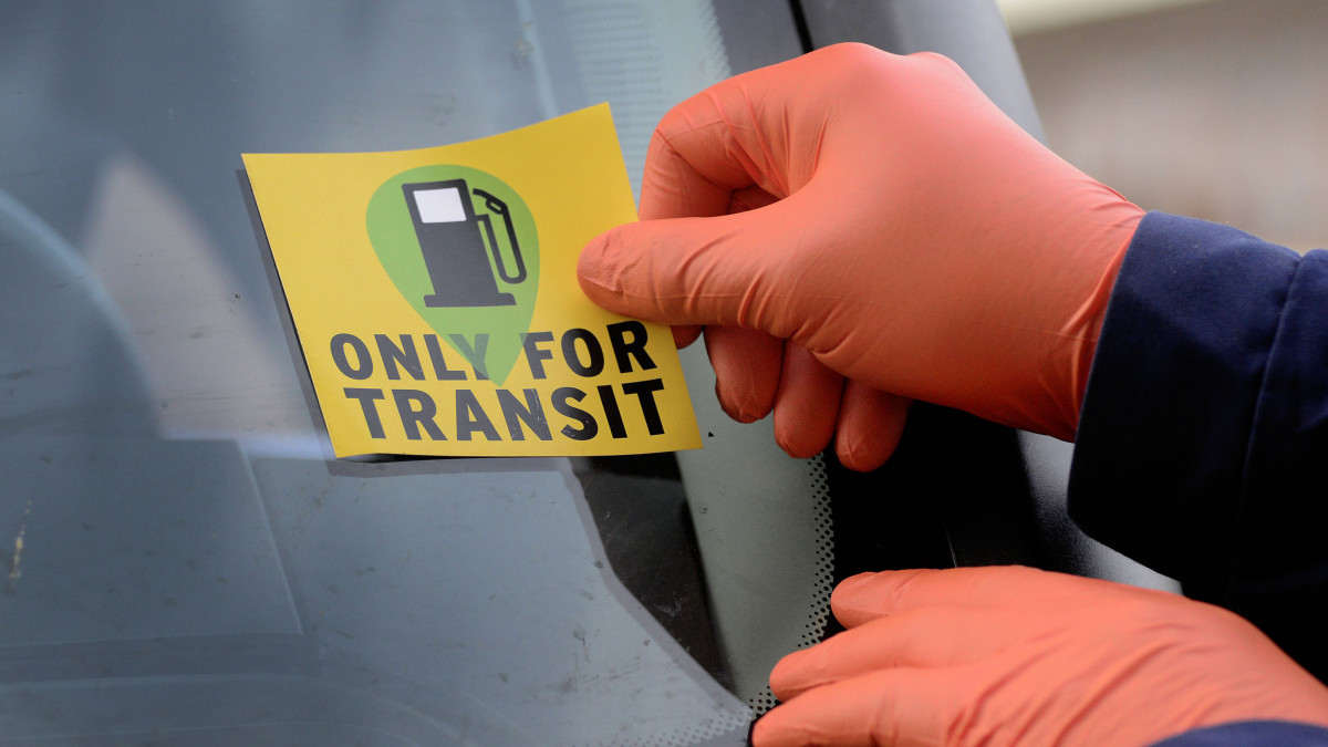 Magyar rendőr Only for transit jelzést ragaszt egy érkező kamionra a magyar-osztrák határon, a hegyeshalmi átkelőn 2020. március 21-én. A koronavírus-járvány miatt Magyarország humanitárius folyosókat nyitott az átutazók számára.