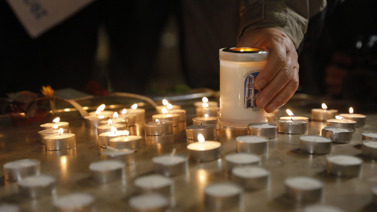 Gyászolók mécseseket gyújtanak az áldozatok emlékére a nizzai Notre-Dame-bazilikánál 2020. október 29-én. Brahim Ausszaui 21 éves tunéziai bevándorló a reggeli órákban késsel támadt a bazilikában tartózkodó három emberre, egy idős nőt lefejezett, a sekrestyést és egy másik nőt halálosan megsebesített.
