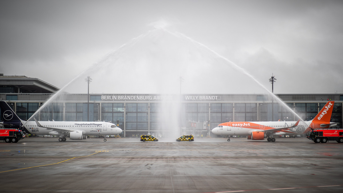 Vízsugárral  locsolják a Berlin-brandenburgi Willy Brandt Nemzetközi Repülőtéren (BER) elsőként fogadott EasyJet (j) és Lufthansa gépet a légikötő megnyitóján a Berlin melletti Schönefeldben 2020. október 31-én. Berlin és a német főváros körüli Brandenburg tartomány új nemzetközi repülőterén az első tervekhez képest kilenc év késéssel indult meg a forgalom.